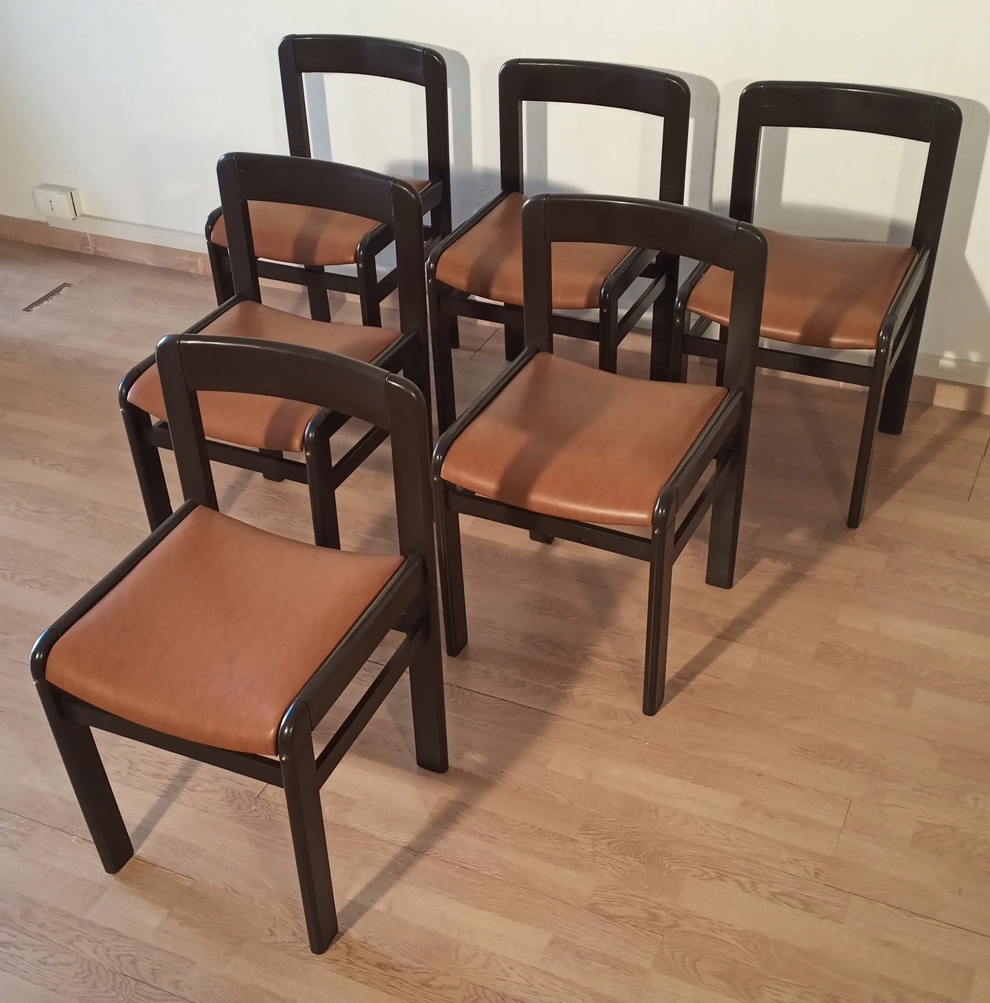 Set di cinque sedie da pranzo vintage in legno nero con sedute in pelle color cuoio anni 70